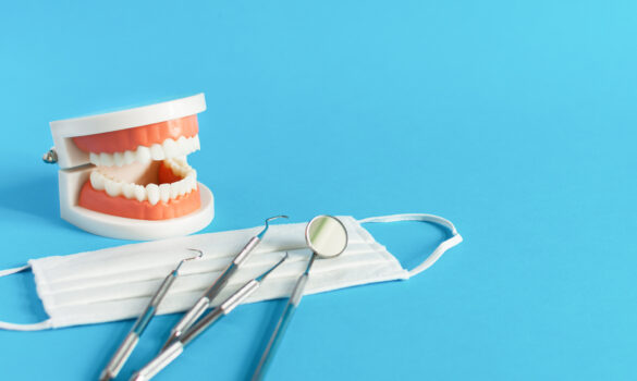 Picture of a teeth model, a surgical mask, and dental tools.