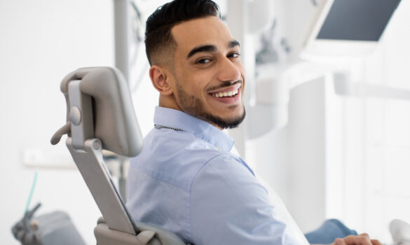 Picture of a man smiling while sitting in an orthodontist chair.