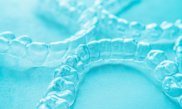 Picture of three Invisalign aligners against a turquoise background.